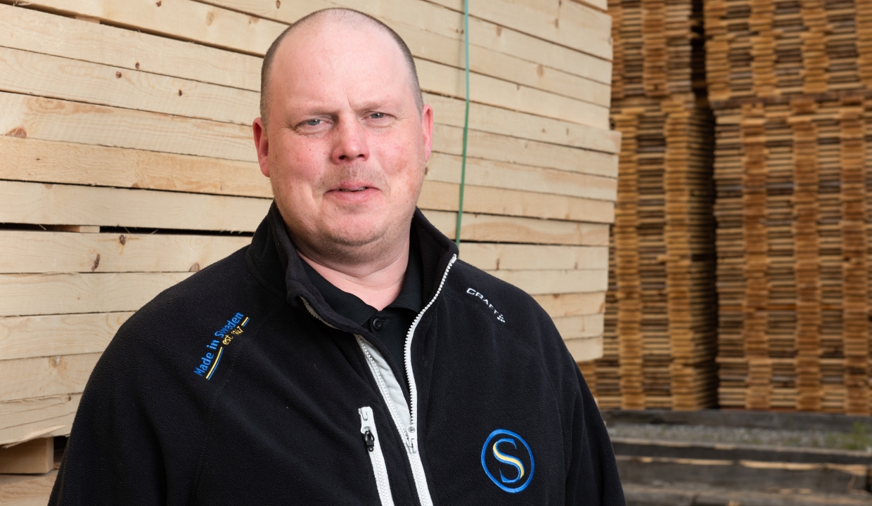 Portrait of our salesperson Krister Backman, standing infront of packages of sawn wood.