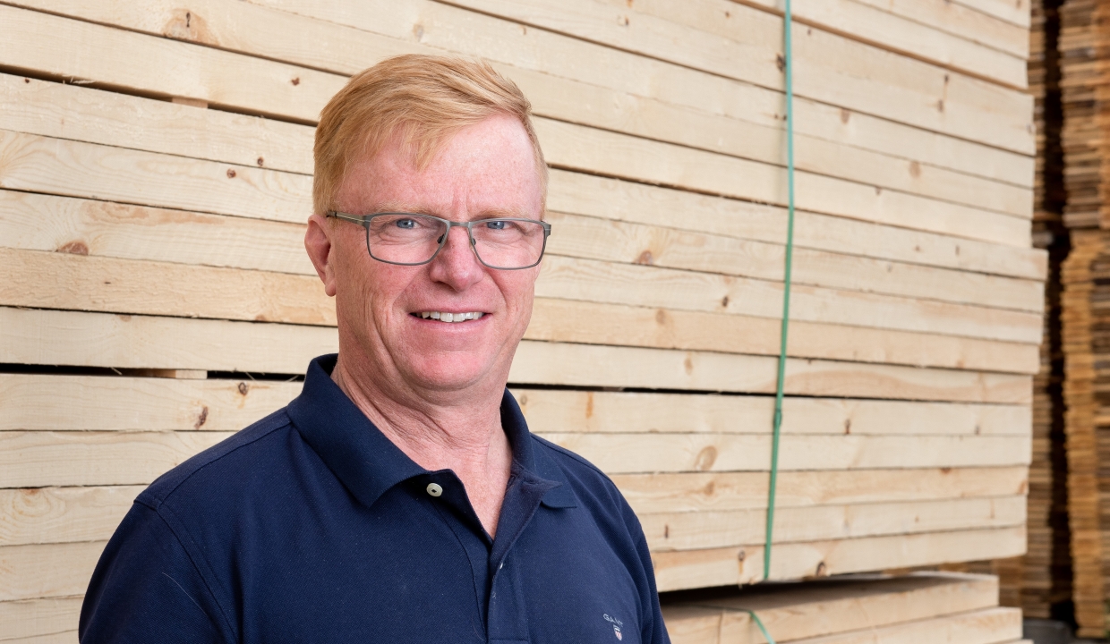 Portrait of our salesperson Thord Fjällström, standing infront of packages of sawn wood.